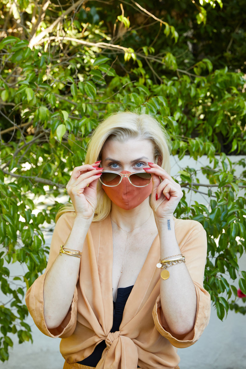 Model against tree background wearing reversible silk face mask and sunglasses
