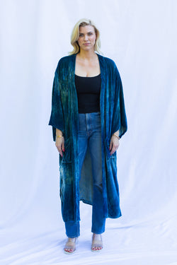 Front view of woman wearing velvet duster in fish scale, a green blue color. 