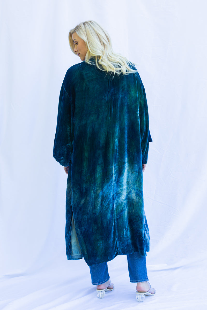 Back view of woman wearing velvet duster in fish scale, a green blue color. 