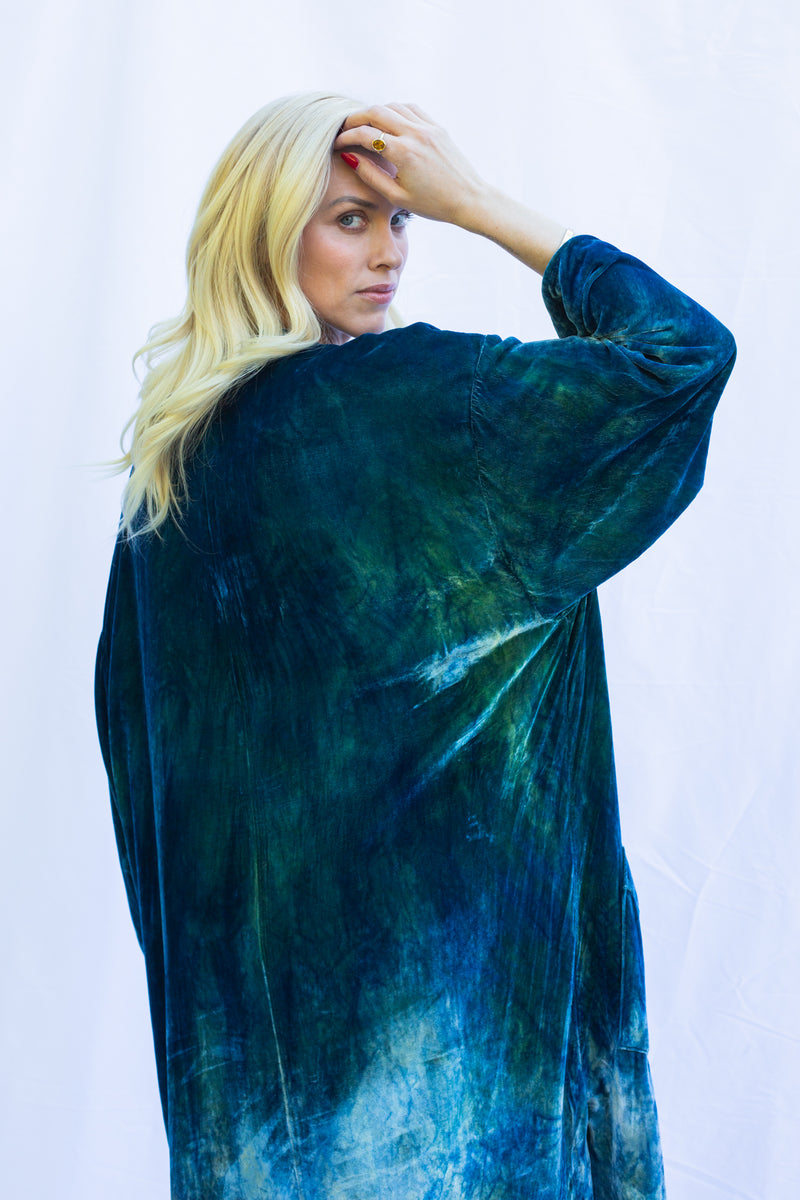 Close up side view of woman wearing velvet duster in fish scale, a green blue color. 