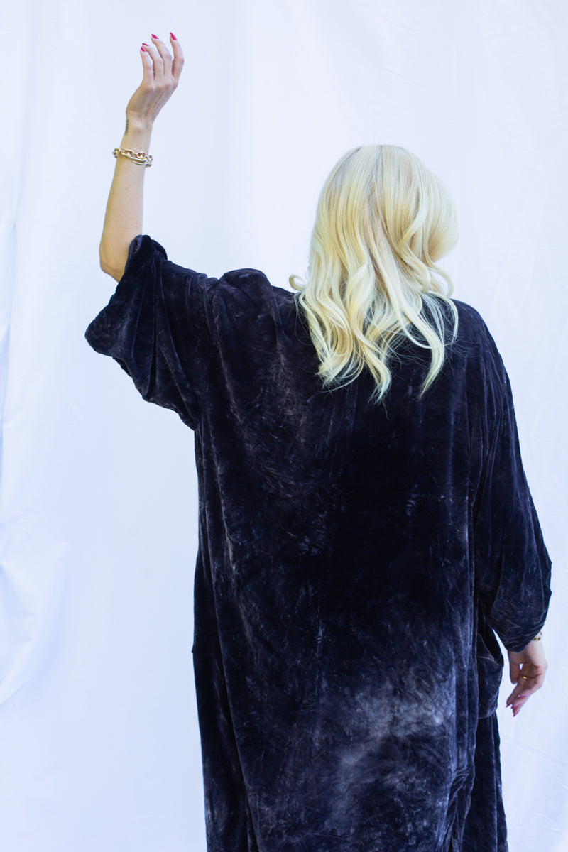 Close up back view of woman holding up arm wearing velvet duster in midnight. 