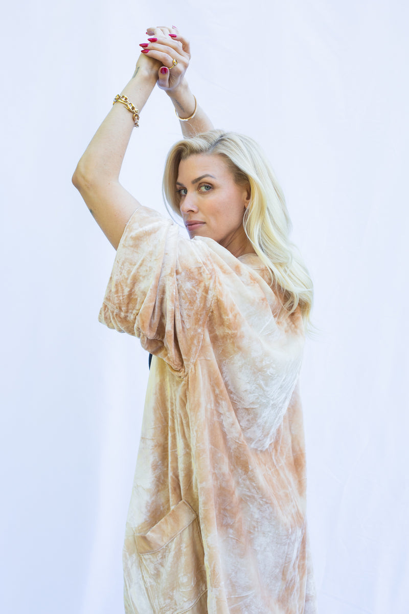 blond women holding up hands wearing velvet duster in marbled light color with peachy tones