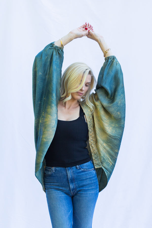 Woman standing with hands over head wearing short duster in Fern (green)