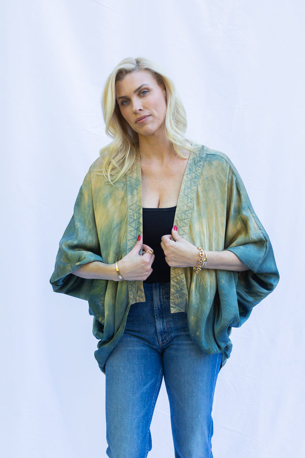 Woman standing with hands on  quilted edge of short duster in Fern (green)