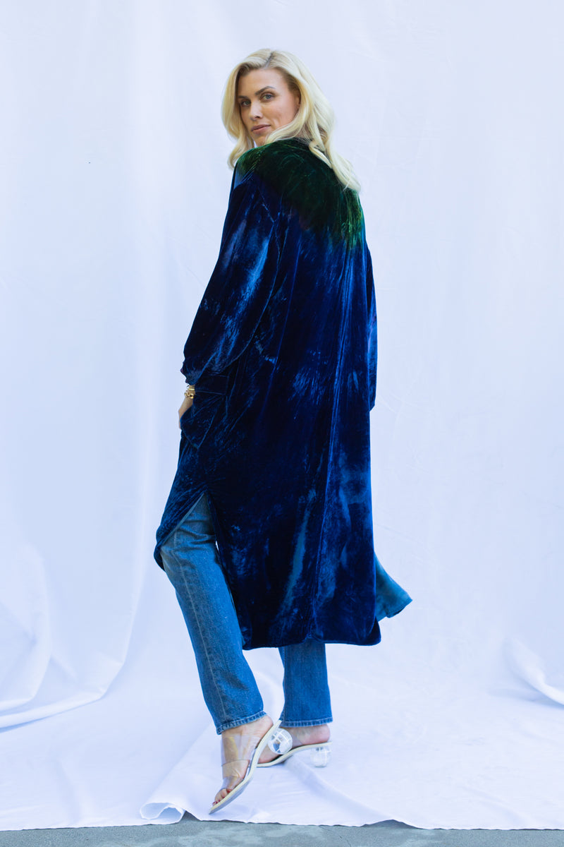 Back side view of velvet duster in emerald night. Woman is looking over shoulder. 