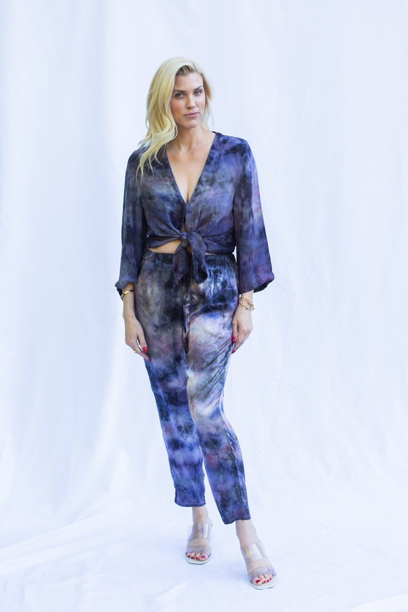 Front view of woman wearing wrap top in cosmica, featuring a tie waist and long sleeves. 