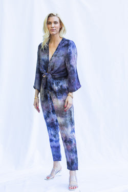 Woman wearing matching set featuring georgette wrap top in cosmica, a purple tie dye color.