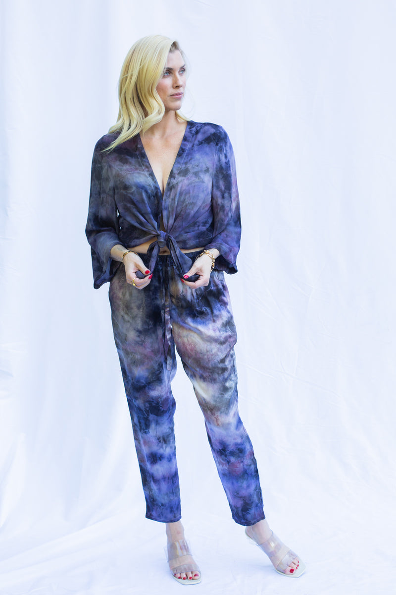 Woman wearing matching set featuring georgette wrap top in cosmica, a purple tie dye color.
