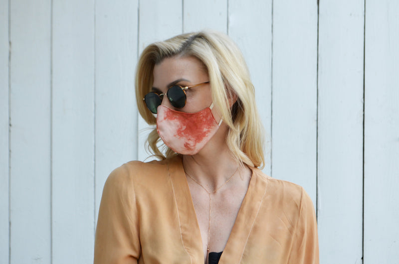 model against white wooden background showing side view of tie dyed reversible silk face mask