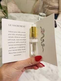 hand holding sample silk spray and card holder describing the scent. 